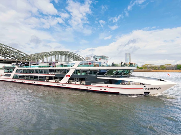 MS RheinMagie Modern excursion boat RheinMagie on the Rhine in front of a large arched bridge in Cologne