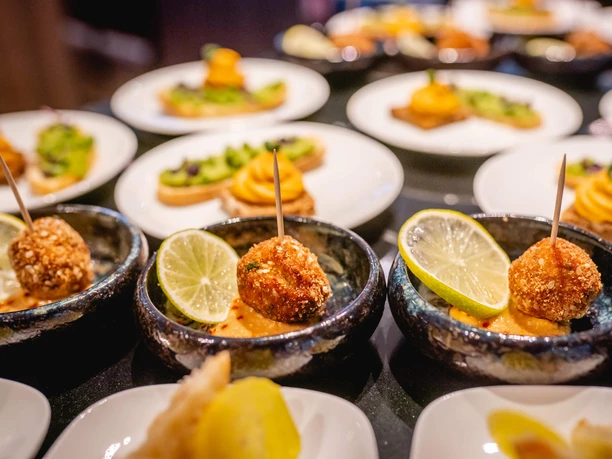 Menü auf-dem Rhein Kleine Schalen mit frittierten Häppchen auf Dip und Limettenscheiben, umgeben von weiteren Vorspeisen.