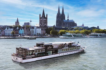 Panoramafahrt Köln Fahrgastschiff auf dem Rhein vor Kölner Altstadt mit markanten Kirchtürmen.