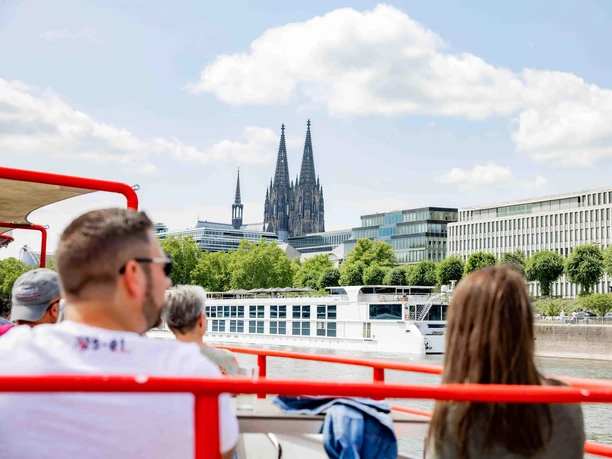 Panoramafahrt Köln Menschen auf Ausflugsschiff mit Blick auf Kölner Dom, Rheinufer und moderne Gebäude