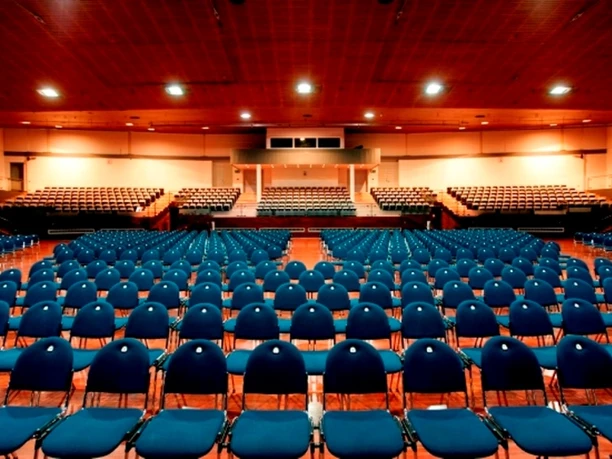 Stadthalle Offenbach - Veranstaltungssaal Bestuhlter Veranstaltungssaal der Stadthalle Offenbach mit Blick von der Bühne auf blaue Stuhlreihen und die Tribüne.
