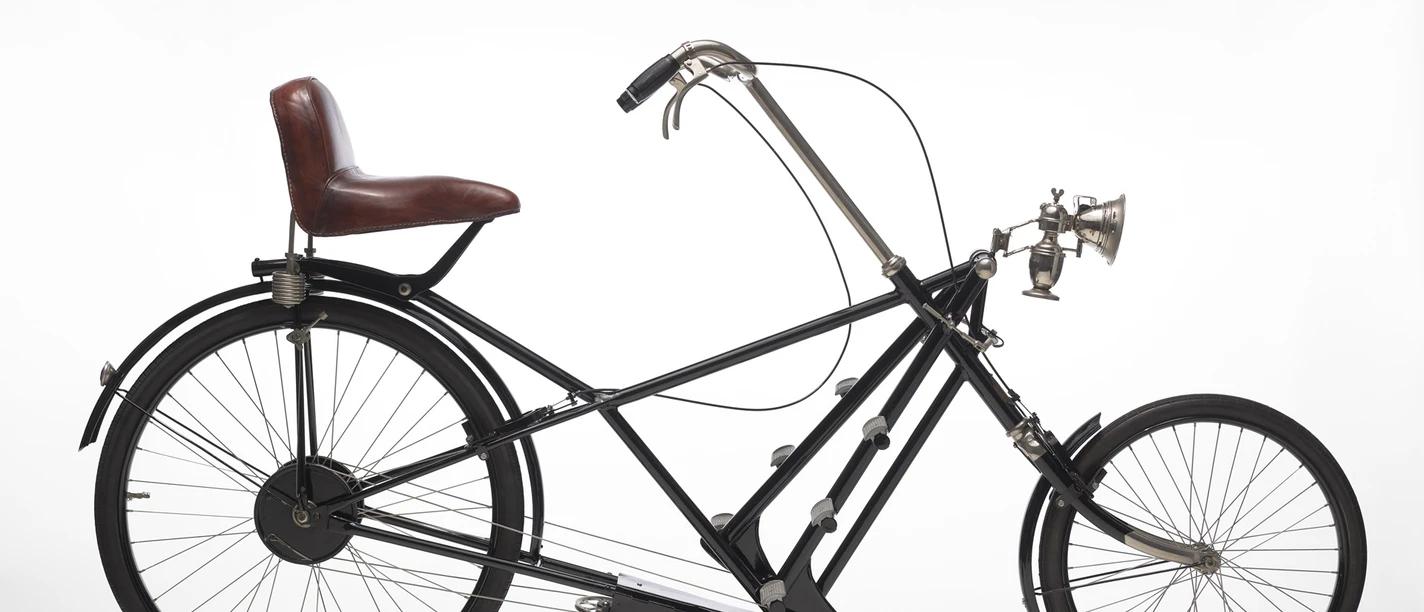 Paul-Jaray_Sesselrad_D_1922_pm_01.jpg Schwarzes historisches Sesselrad von 1922 mit kleinem Vorderrad und braunem Ledersitz mit Lehne.