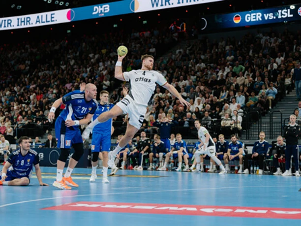 Handball (symbolic image) Handball player taking a jump shot in front of an opponent's defense in a crowded arena.