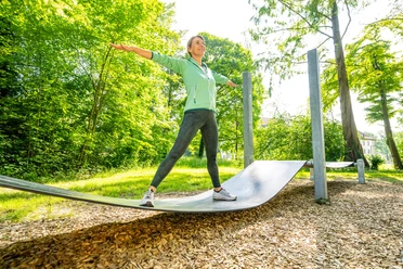Frau trainiert auf geschwungener Fitnessstation im Eggeland-Park Bad Driburg.