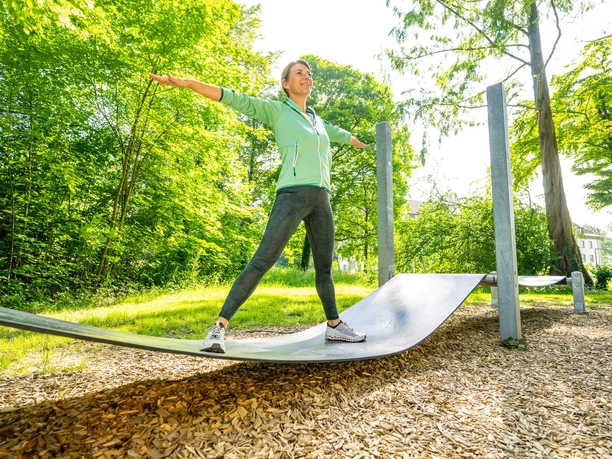 Frau trainiert auf geschwungener Fitnessstation im Eggeland-Park Bad Driburg.
