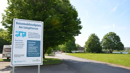 Wohnmobilstellplatz_Salzgittersee_HD_16zu9.JPG Weißes Hinweisschild für den Reisemobilstellplatz am Salzgittersee an einer Zufahrtsstraße.