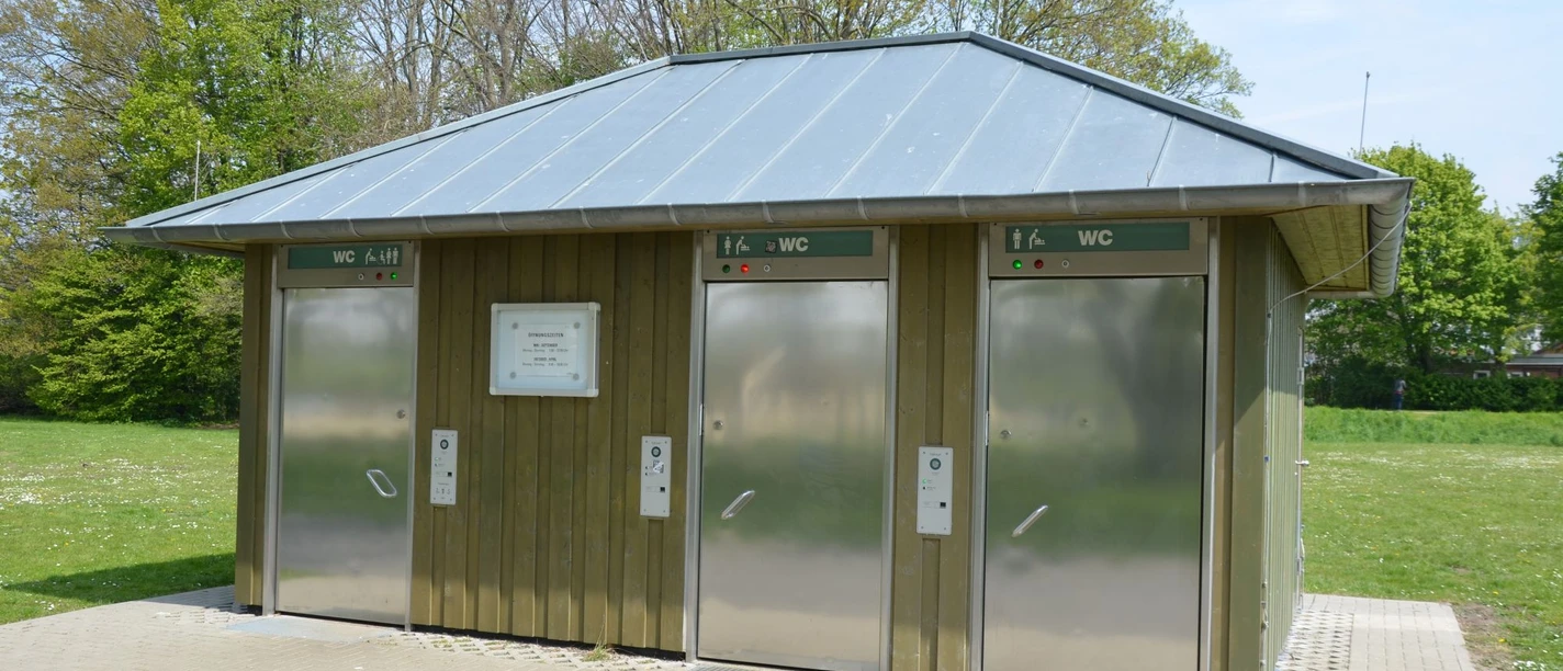 Toilettenanlage_Piratenspielplatz_HD_16zu9.JPG Öffentliche, barrierefreie WC-Anlage am Piratenspielplatz mit Holzverkleidung und Edelstahltüren.