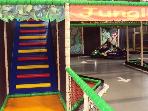 HallyGally Salzgitter(11)_HD_16zu9.JPG Bunter Indoorspielplatz mit Kletterrampe und einer Gokart-Bahn im Dschungel-Design.