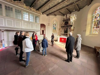 Gästeführung vor dem Altar der Kirche Eine Besuchergruppe bei einer Führung im historischen Altarraum der St.-Ulrichs-Kirche.