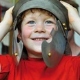 Familienführung in der Ausstellung zur Varusschlacht Ein lachender Junge trägt einen antiken Heldenhelm und blickt fröhlich in die Kamera.