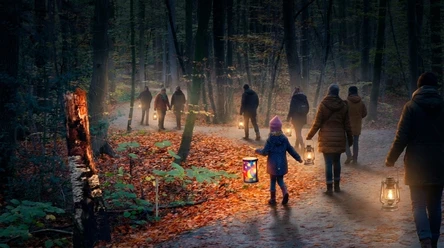 Laternenwanderung im Schlosspark bei Dunkelheit Menschen mit leuchtenden Laternen bei einem Abendspaziergang im herbstlichen Wald.