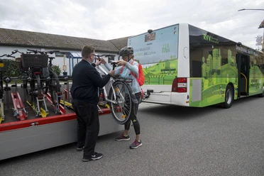 Fahrradbus nach Falkenstein Person lädt mit Fahrer ein Fahrrad auf einen Anhänger hinter einem grünen Bus der Linie 34.