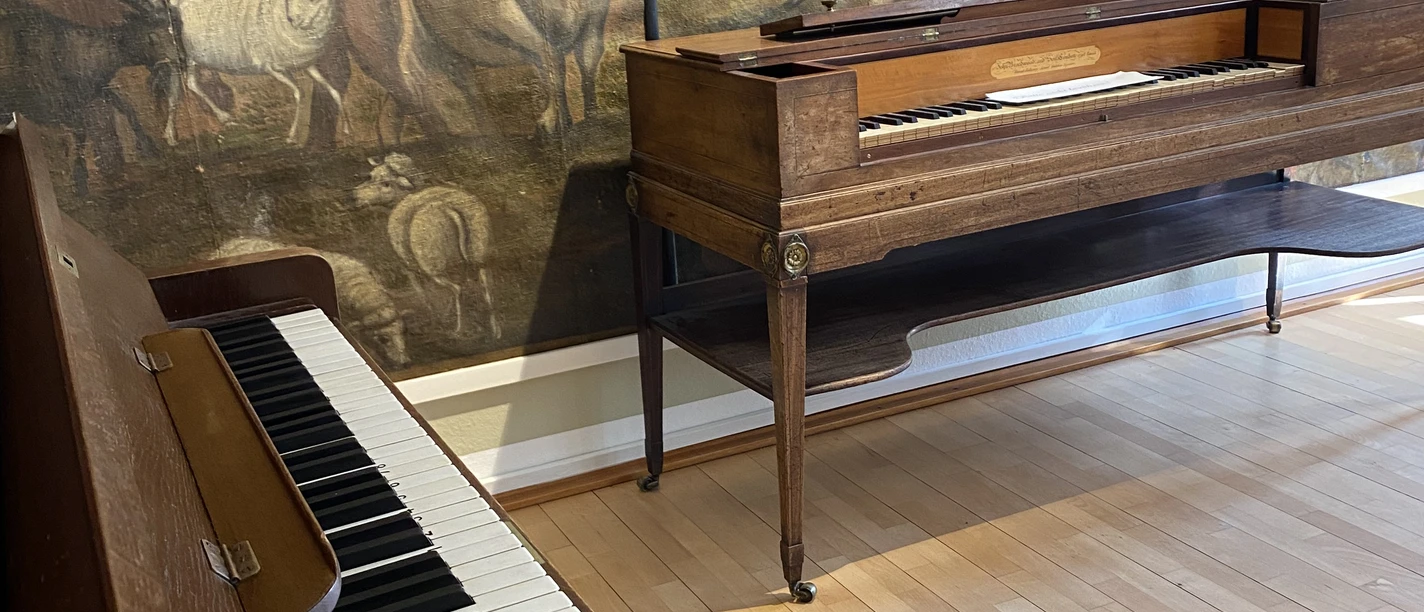 Frühlingssingen, ©StadtMuseum Einbeck.jpeg Historisches Klavier im Vordergrund, dahinter ein zweites Tasteninstrument und ein großes Gemälde.