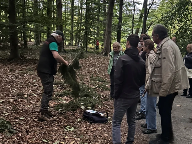 Waldbegehung Schloss Benkhausen Forstmann erklärt Gruppe bei Waldbegehung Zweige und Baumpflanzung im Wald bei Schloss Benkhausen