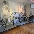 Radhaus 19.jpg Historische Fahrräder, darunter ein Hochrad, ausgestellt im Museum vor großformatigen Wandbildern.