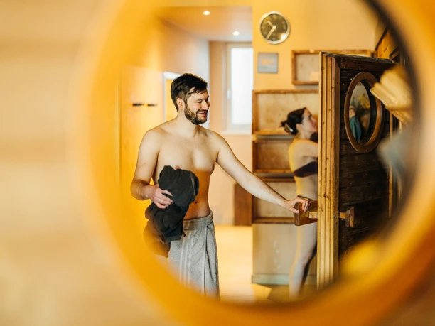 À travers le hublot rond, on aperçoit un couple qui s'apprête à entrer dans le sauna finlandais du sauna dans le lac.