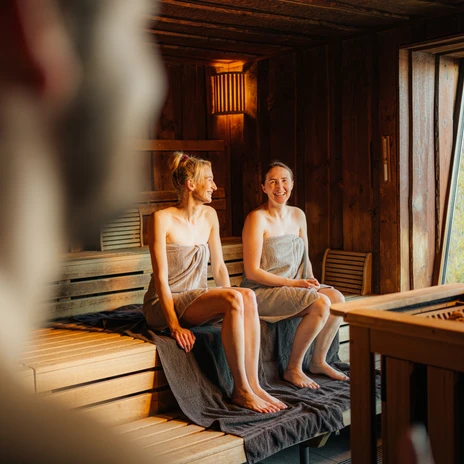 Sauna panoramique du Sauna im See - Bien-être à Leipzig et dans la région Deux femmes assises en riant avec leurs serviettes dans le sauna panoramique du sauna dans le lac