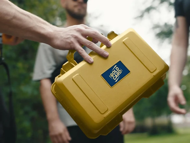 outdoor escape game Hand holding golden puzzle case in front of several people outdoors