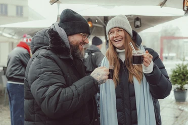 Epic Escape Two people in winter coats drink hot mulled wine outside and laugh together