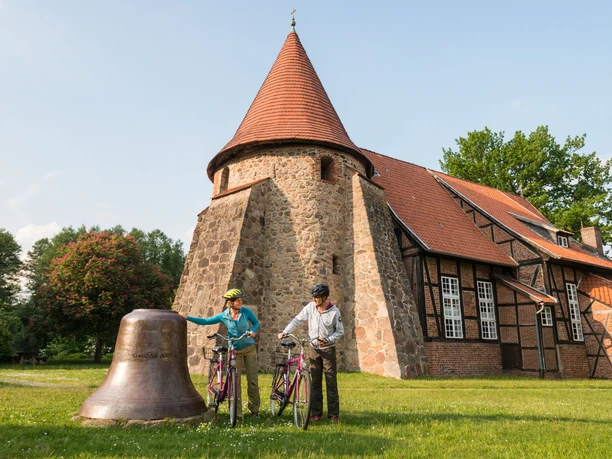 Radfahrer an der Feldsteinkirche Suderburg bei Uelzen Zwei Radfahrer stehen mit ihren Fahrrädern vor der Feldsteinkirche Suderburg in Niedersachsen
