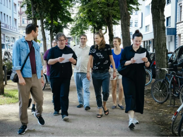 Stadtspaziergang1 Gruppe beim Stadtspaziergang auf einer von Bäumen gesäumten Straße in Köln