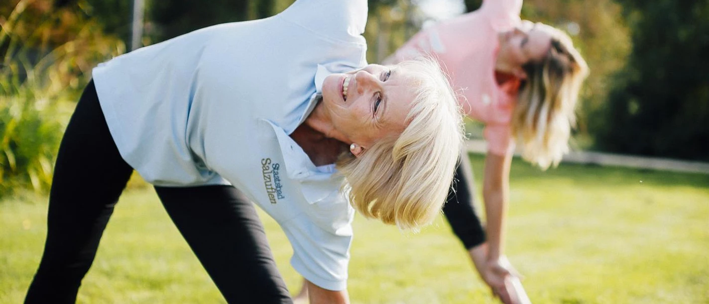 Zwei Frauen machen Gymnastik auf einer Wiese im Kurpark Bad Salzuflen
