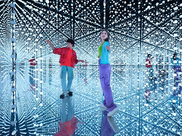 BUBBLE PLANET Zwei Personen in spiegelndem Raum mit vielen leuchtenden Kugeln