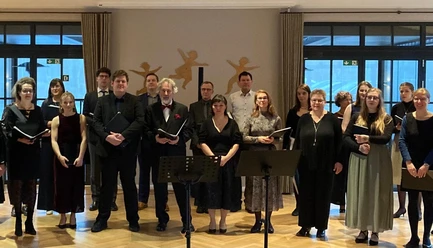 Das Gesangensemble Ein gemischter Chor in dunkler Kleidung steht mit Notenmappen für ein Konzert bereit.