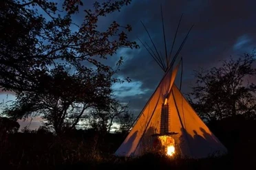 Trommelsession im Tipi Erleuchtetes Tipi bei Nacht. Schattenrisse der Gäste versprechen ein magisches Abenteuer.