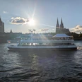 The Kölntourist passenger boat trip on the Rhine in Cologne Passenger ship on the Rhine in front of Cologne Cathedral backlit by the low sun