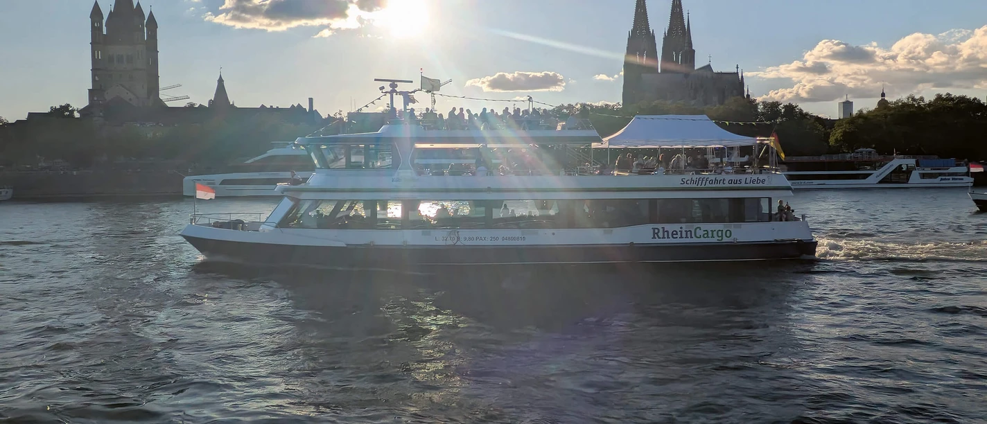 The Kölntourist passenger boat trip on the Rhine in Cologne Passenger ship on the Rhine in front of Cologne Cathedral backlit by the low sun