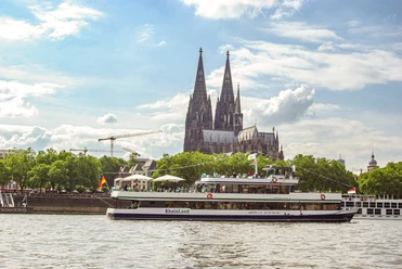 Die Kölntourist Personenschiffahrt am Ufer der Kölner Altstadt Ausflugsschiff RheinLand vor großer Kathedrale am Rhein unter weitläufigem Sommerhimmel