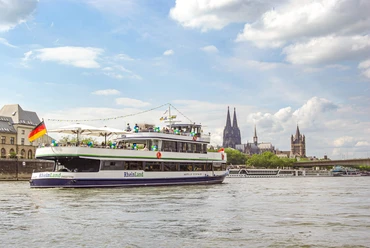 Die Kölntourist Personenschiffahrt auf dem Rhein in Köln Ausflugsschiff auf dem Rhein vor Kölner Skyline mit Kathedrale und Uferbebauung