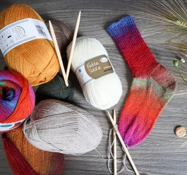 sockenwolle_knaeuel.jpg Bunte Wollknäuel mit handgestrickter Socke und Stricknadeln