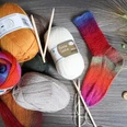 sockenwolle_knaeuel.jpg Bunte Wollknäuel mit handgestrickter Socke und Stricknadeln