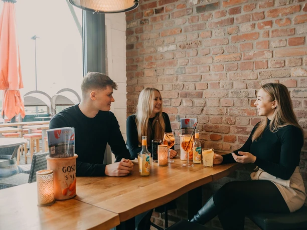 Drei junge Menschen sitzen in einem Restaurant zusammen