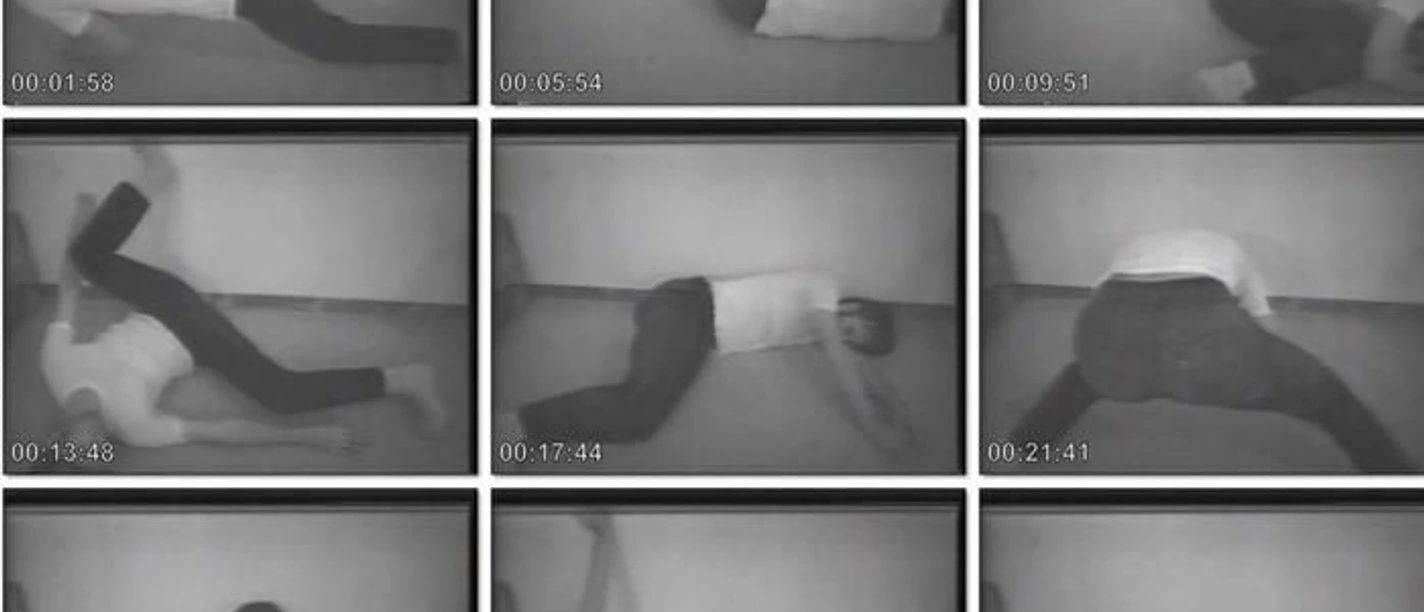 Eine Collage aus schwarz-weiß-Fotografien sitzt oder liegt eine Person in unterschiedlichen Positionen auf dem Boden vor einer Wand.