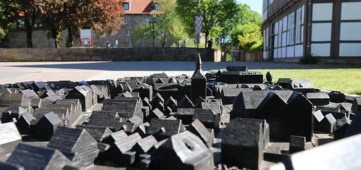 Bronzenes Stadtmodell vor Fachwerkhaus und Stadtmauer in Blomberg
