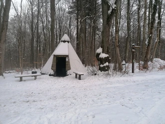 Köhlerhütte im Schnee Verschneite Köhlerhütte in einem Winterwald bei Einbeck. Daneben stehen eine Bank und ein Wegweiser.