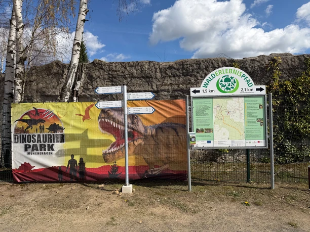 Wegweiser Rehburg-Loccum Waldblicke Wegweiser und Infotafel zum Entdeckerpfad Waldblicke neben einem Banner des Dinosaurier-Parks.