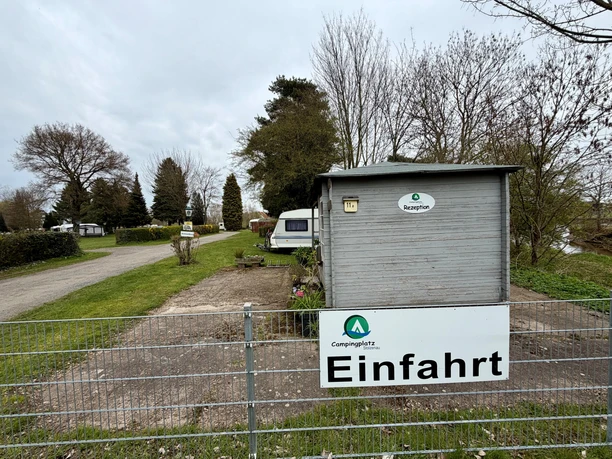Campingplatz Stolzenau 2 Einfahrt zum Campingplatz Stolzenau mit hölzerner Rezeptionshütte und Hinweisschild.