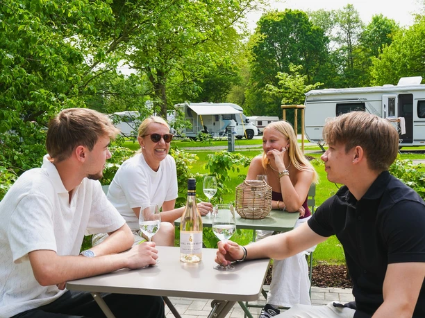 Vier Personen sitzen um zwei Tische herum auf dem Heimatcampingplatz Lemgo