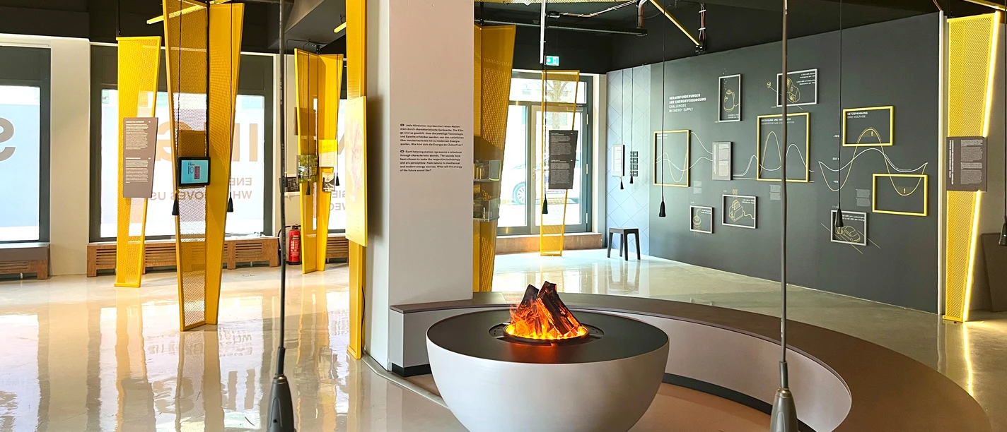 Blick in den Ausstellungsraum "Energie – Was uns bewegt" mit Schautafeln und einem künstlichen Lagerfeuer