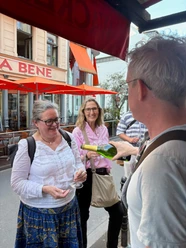 Pläsierchen- Genussvolle Stadttour Gruppe probiert Wein im Straßenbereich mit roten Markisen