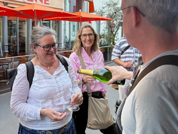 Pläsierchen- Genussvolle Stadttour Gruppe probiert Wein im Straßenbereich mit roten Markisen