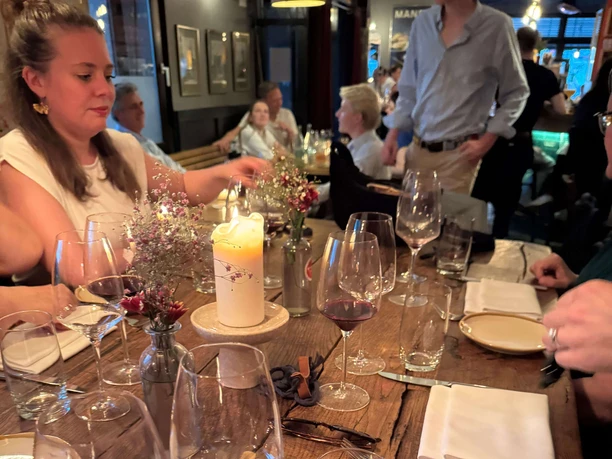 A Delightful City Tour Convivial table with candle, wine and water glasses in a lively interior.