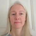 Dr. Nina Hennig - Leiterin Museumsfachstelle-Volkskunde bei der Ostfriesischen Landschaft Porträt einer älteren Frau mit langen hellen Haaren und grauem Pullover vor einer weißen Wand.