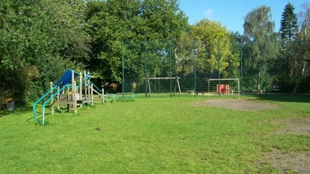53 Lübecker Str_WEB.jpg Klettergerüst und Bolzplatz am Spielplatz Lübecker Straße, umgeben von üppigem Baumbestand