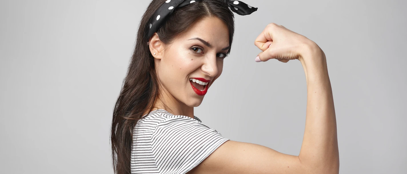 Portrait of strong independent female wearing headscarf and stylish sailor shirt showing her bicep at camera, having excited expression. People, strength, power, sports, energy and fitness concept Portrait of strong independent female wearing headscarf and stylish sailor shirt showing her bicep at camera, having excited expression. People, strength, power, sports, energy and fitness concept