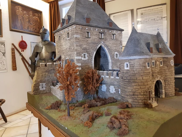 Zollmuseum Friedrichs_Mittelalter (c) Zollmuseum Friedrichs.jpg Das Modell einer mittelalterlichen Burg sowie eine Ritterrüstung sind in einem Museumsraum ausgestellt.